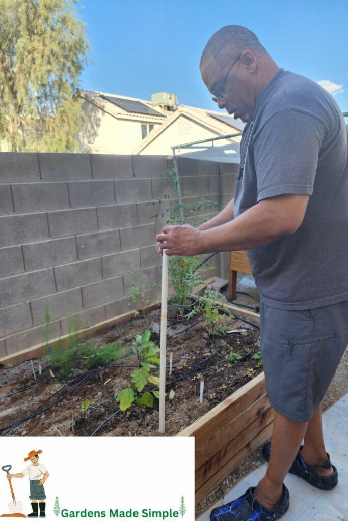 Man using the Seed Planting Technique using PVC Tube Pipe to make holes and  for planting Seeds Drop Through the Hole in the Pipe.